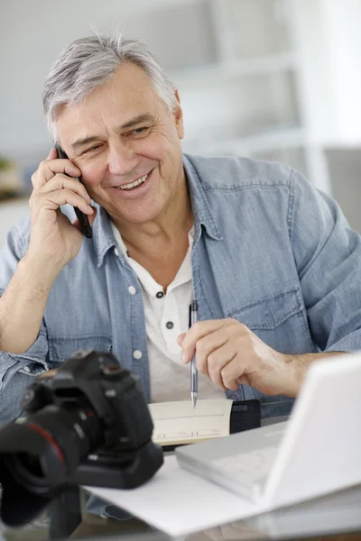 Fotograf i office prata med klienten på telefonen — Stockfoto