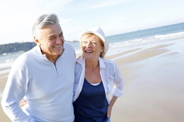 Senior koppel wandelen op het strand in vallen seizoen — Stockfoto