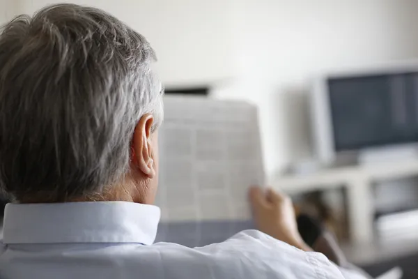 Vista posterior del hombre leyendo el periódico en casa — Foto de Stock