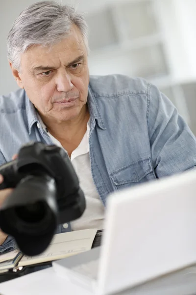 Senior reporter pracuje w biurze przed laptopa — Zdjęcie stockowe