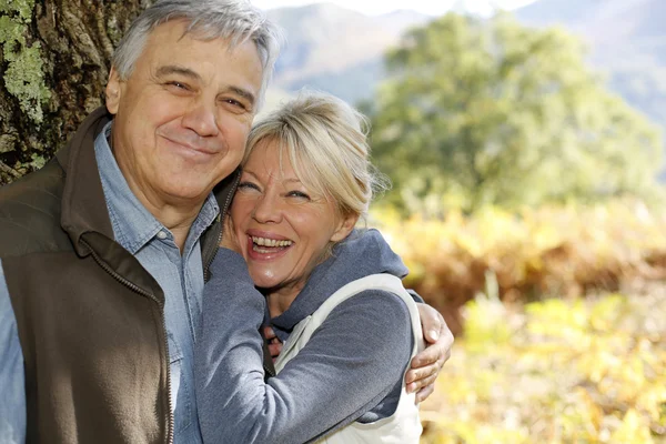 Portrait de couple âgé souriant appuyé contre l'arbre — Photo