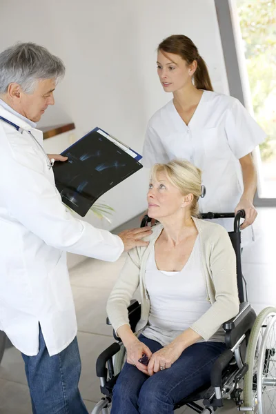 Médico y enfermera hablando con el paciente en silla de ruedas — Foto de Stock