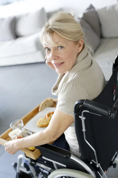 Senior mulher em cadeira de rodas segurando bandeja de almoço — Fotografia de Stock