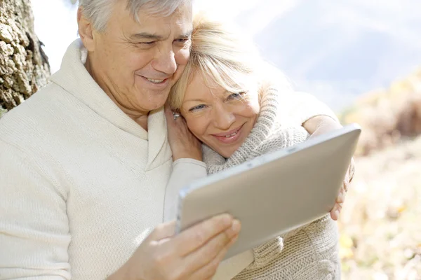 Äldre par med hjälp av Tablet PC i skogen Stockfoto