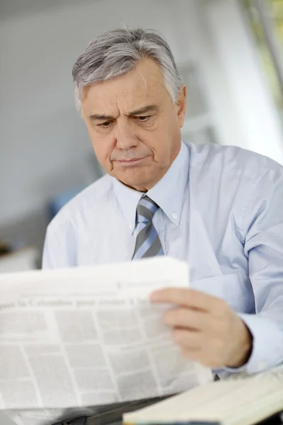 Старший бізнесмен читає газету з спантеличеним виглядом Ліцензійні Стокові Зображення
