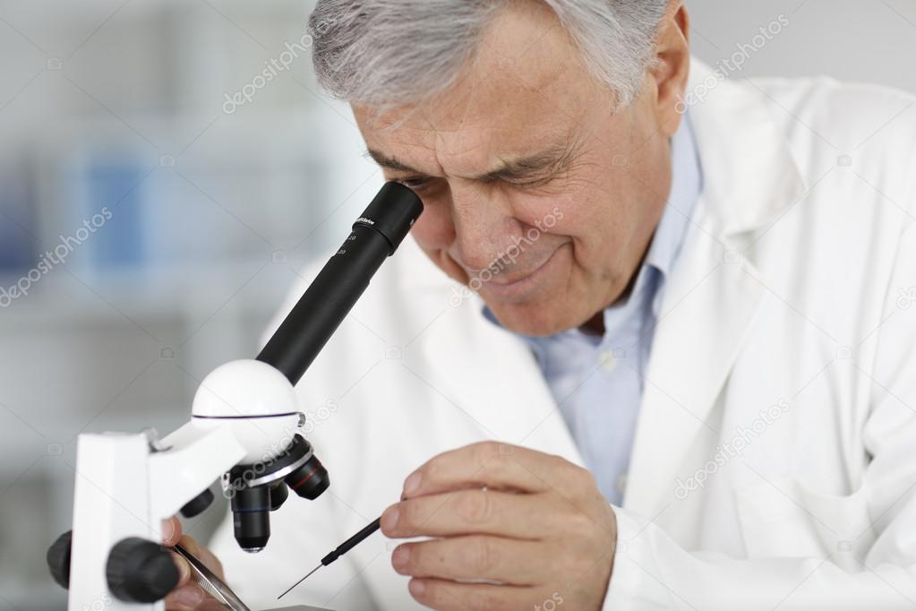 Scientist in lab looking through microscope lens