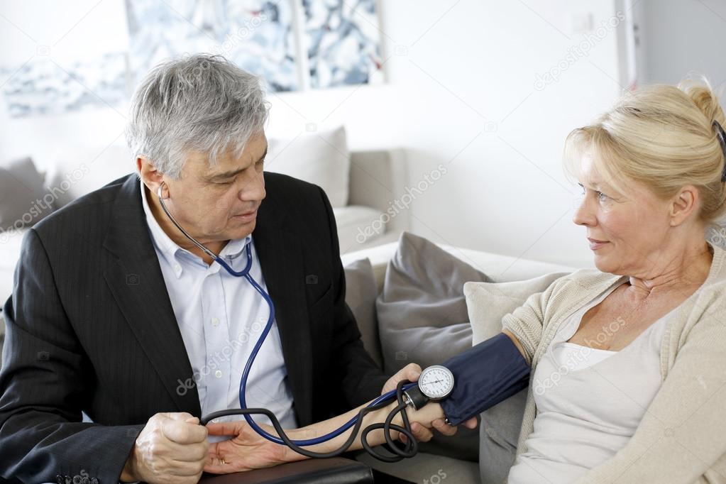 Doctor taking blood pressure to patient at home