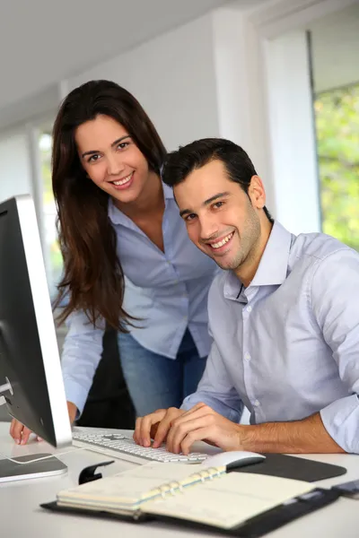 Jovens trabalhadores de escritório na frente do computador desktop — Fotografia de Stock