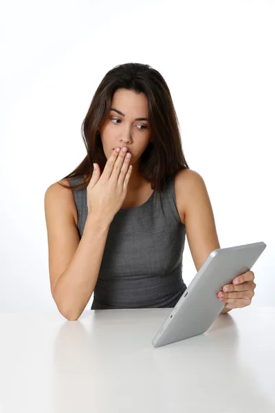 Brunette meisje met geschokt uitdrukking bij kijken naar Tablet PC — Stockfoto