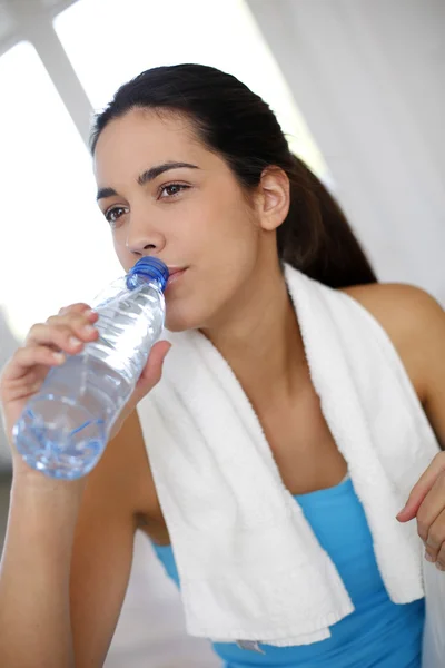 Mujer joven bebiendo agua después de hacer ejercicio — Foto de Stock