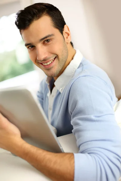 Jonge man met tablet zitten in Bank — Stockfoto