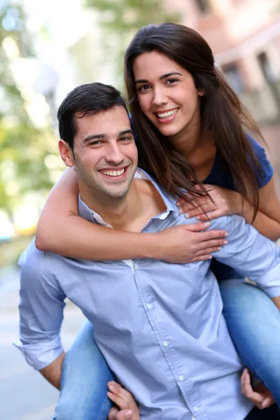 Vrolijke jonge man met vriendin op zijn rug — Stockfoto