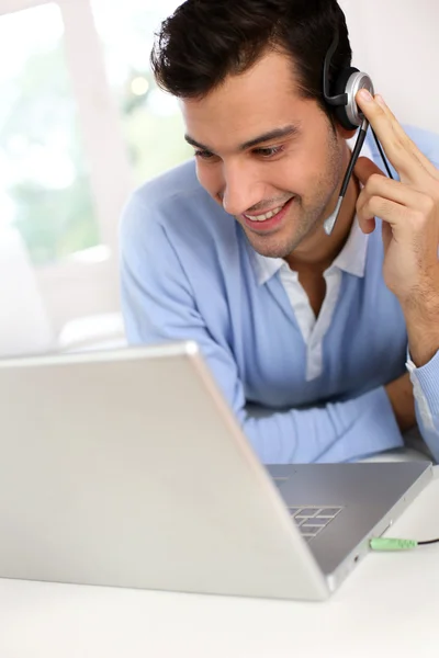 Jovem com fone de ouvido conversando através da webcâmera — Fotografia de Stock