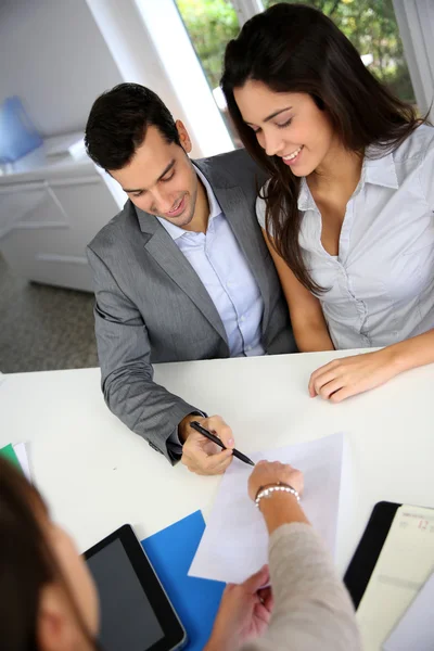 Casal jovem que assina contrato financeiro — Fotografia de Stock