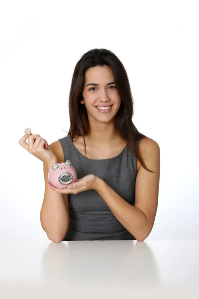 Smiling girl inserting coing in piggy bank — Stock Photo, Image