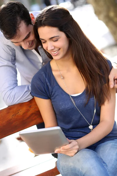 Couple sitting on public bench and using tablet — Stock Photo, Image