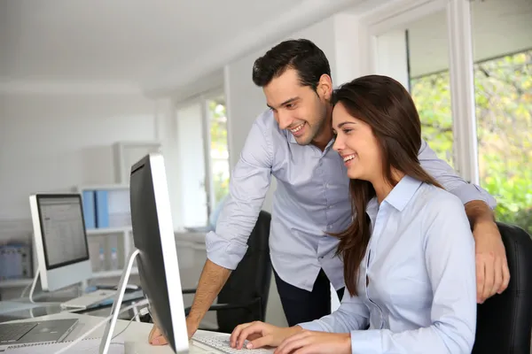 Young office workers in front of desktop computer — Stock Photo, Image