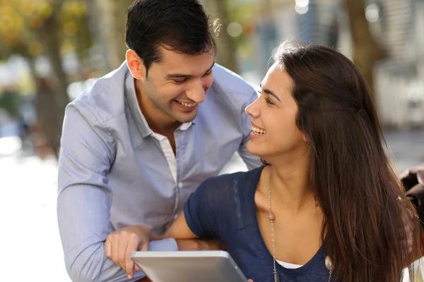 Couple assis sur un banc public et utilisant une tablette — Photo