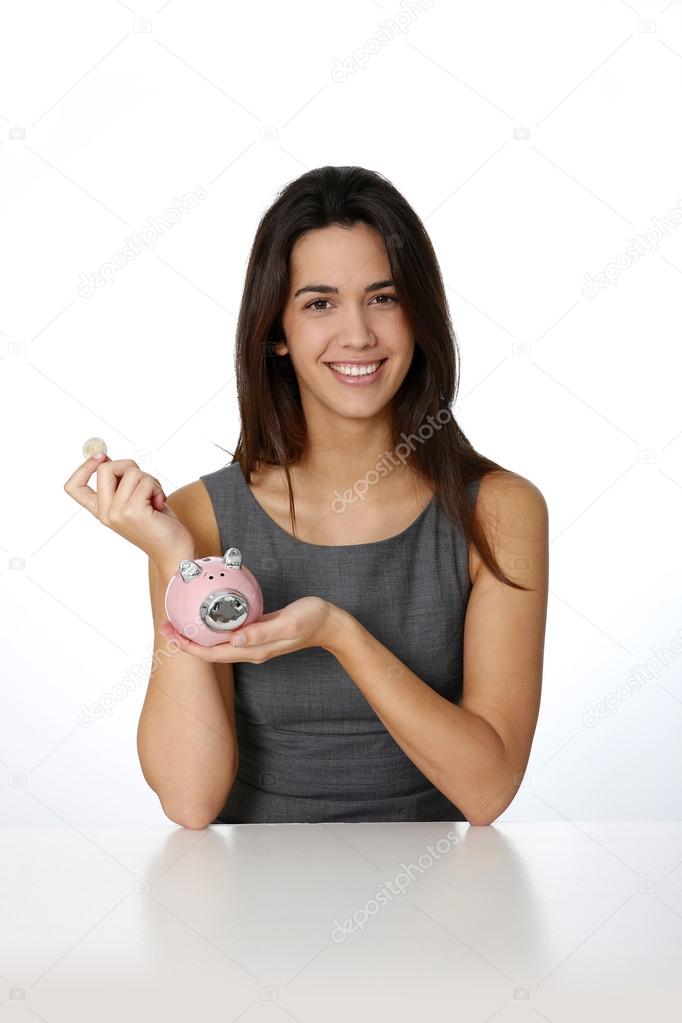 Smiling girl inserting coing in piggy bank