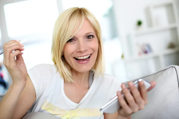 Mujer joven sonriente en casa usando teléfono inteligente — Foto de Stock