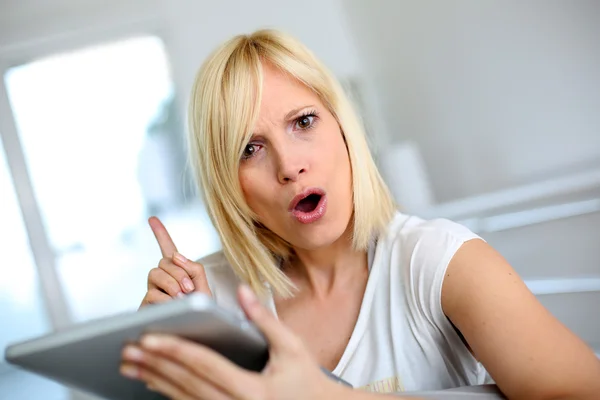 Mulher loira usando tablet com expressão de aviso — Fotografia de Stock