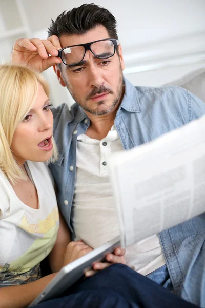 Paar liest Nachrichten mit entsetztem Blick — Stockfoto