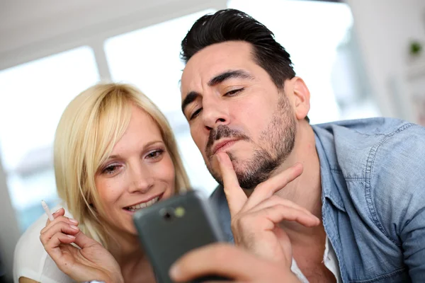 Cheerful couple having fun using smartphone — Stock Photo, Image