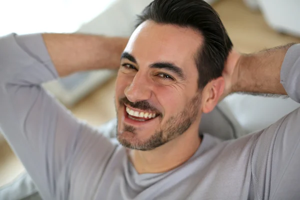 Relaxed man stretching arms behind head — Stock Photo, Image