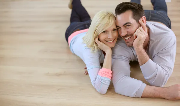 Sweet loving couple laying on wood flooring — Stock Photo, Image