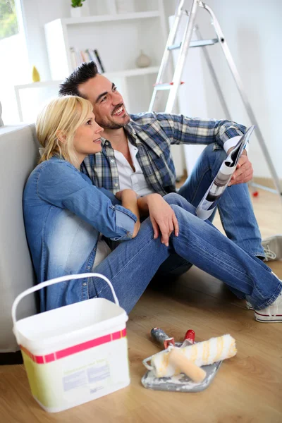 Pareja sentada en el suelo eligiendo el color de la pintura —  Fotos de Stock