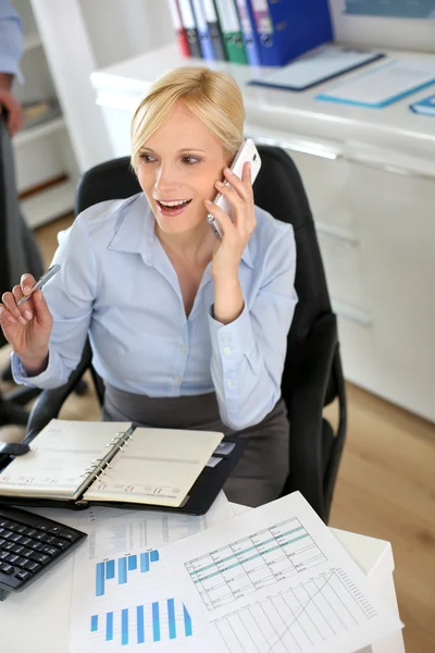 Empresária ao telefone escrevendo na agenda — Fotografia de Stock