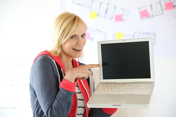 Νεαρή γυναίκα που δείχνει στην οθόνη του φορητού υπολογιστή — Φωτογραφία Αρχείου