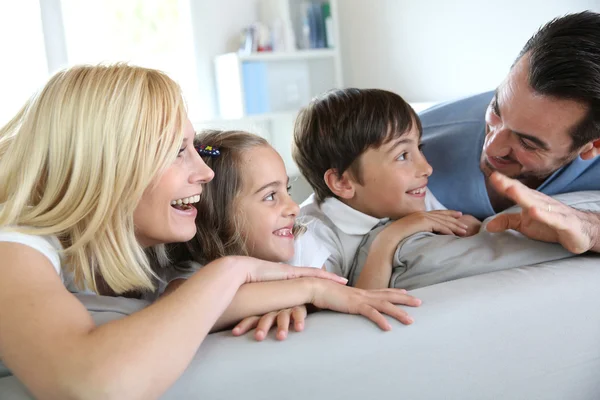 Familj på fyra sitter i soffan hemma — Stockfoto