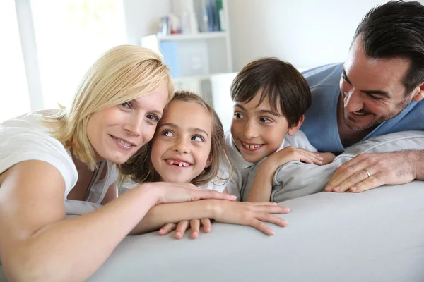 Familj på fyra sitter i soffan hemma — Stockfoto