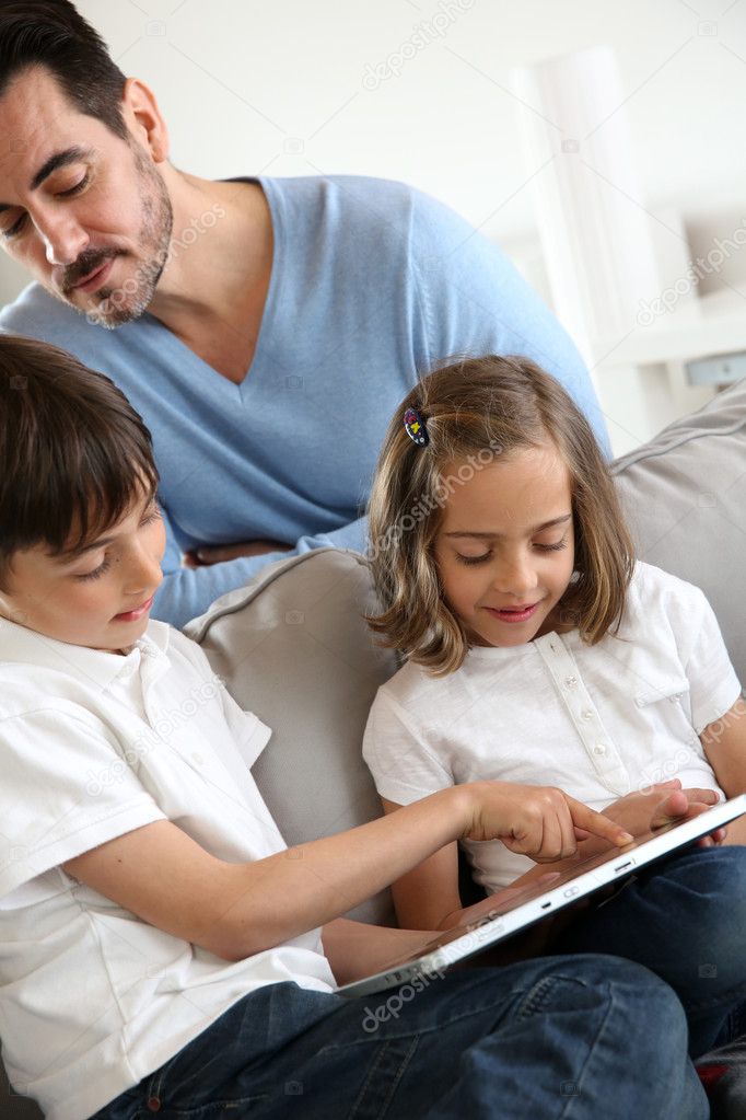 Children with daddy at home using digital tablet