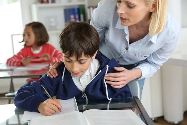Учитель помогает молодому мальчику с уроком — стоковое фото