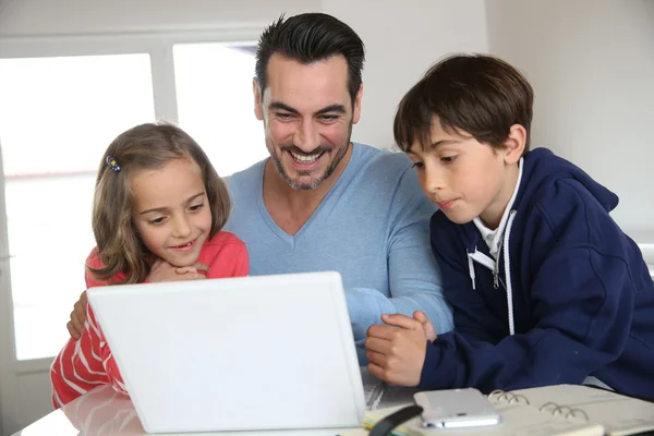 Man med barn som använder bärbar dator hemma — Stockfoto