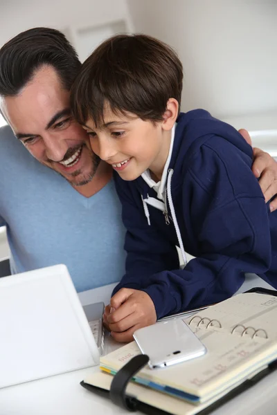 Man showing to young boy how to use laptop — Stock Photo, Image