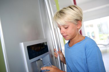 Young boy drinking water from fridge clipart