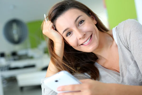 Frau entspannt zu Hause und nutzt Smartphone — Stockfoto