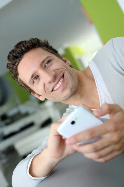 Homme souriant dans le canapé en utilisant le téléphone — Photo