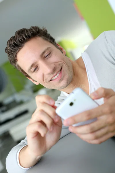 Hombre sonriente en el sofá usando el teléfono — Foto de Stock