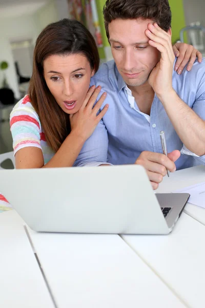 Pareja mirando a la cuenta bancaria con expresión impactada — Foto de Stock