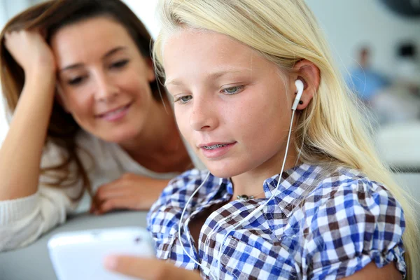 Teenager using smartphone with adult beside her — Stock Photo, Image