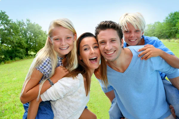 Parents giving piggyback ride to kids in countryside — Stock Photo, Image