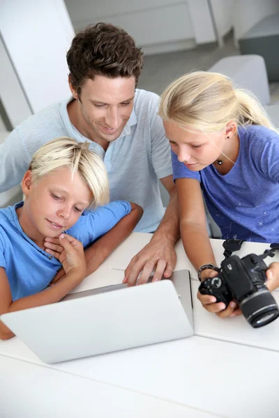 Мужчина с подростками смотрит на картинки на компьютере — стоковое фото