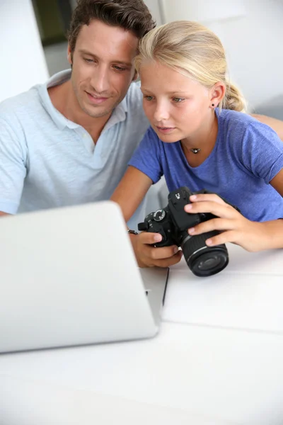 Pai e filha olhando para câmera digital e laptop — Fotografia de Stock