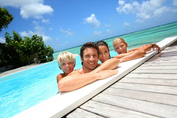 Семья из четырех человек купается в бассейне — стоковое фото
