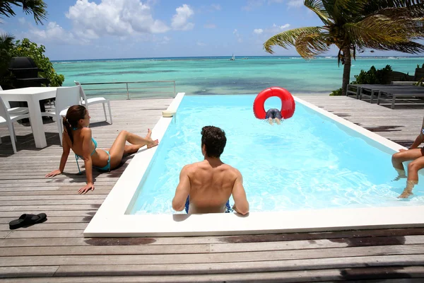 Familia colgando alrededor de la piscina infinita junto al mar —  Fotos de Stock