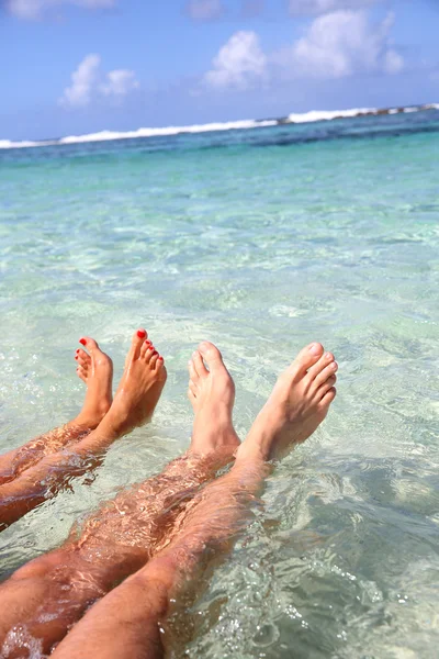Close-up van het echtpaar voeten in het water van de lagune — Stockfoto